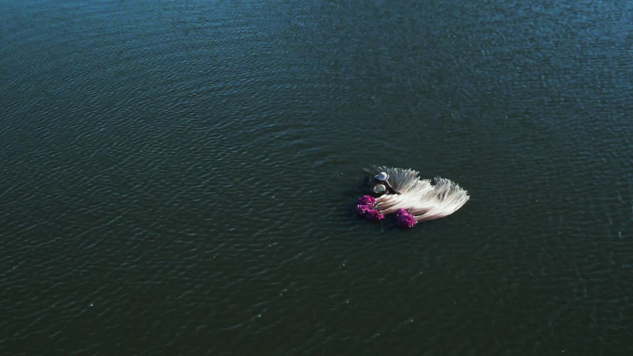 Water lily harvesting.  Worker transport his crop of Lotus floating on lake in Asia - Drone Lift.