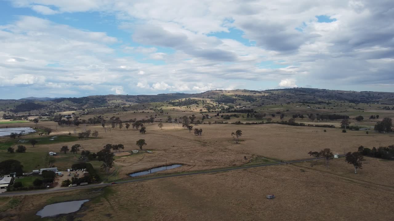 Aerial view of a country road with a car travelling on it as well as dams and farms