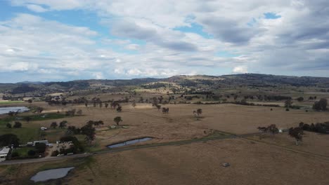 aerial view of a country road with a car travelling on it as well as dams and farms