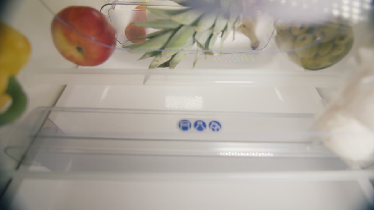 노인 여성이 냉장고에 제품을 로드합니다.