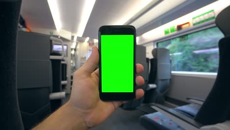 mano sosteniendo un teléfono con una pantalla verde en el tren