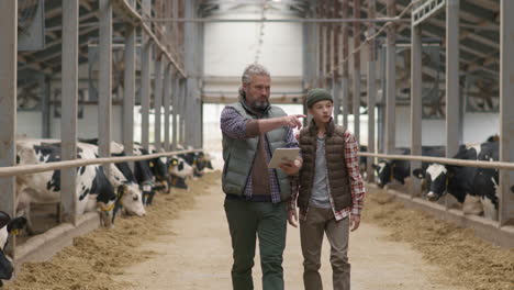 father and teenage son walking through dairy farm