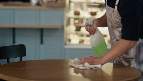 caucasian man with down syndrome cleaning table in the cafe.