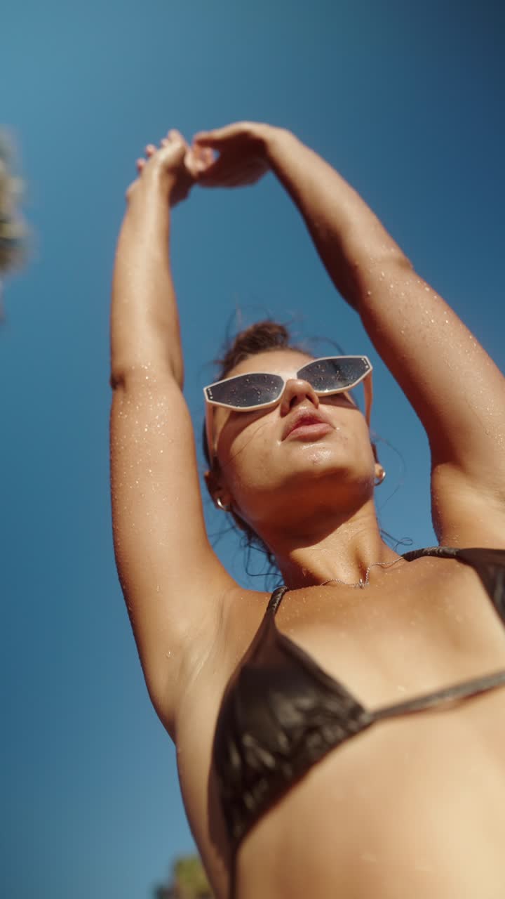 Donna in bikini e occhiali da sole su una spiaggia assolata