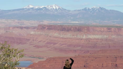 toma en cámara lenta de una turista mostrando el signo de la paz con la mano frente a la vista desde el parque estatal dead horse point en utah, ee.uu.