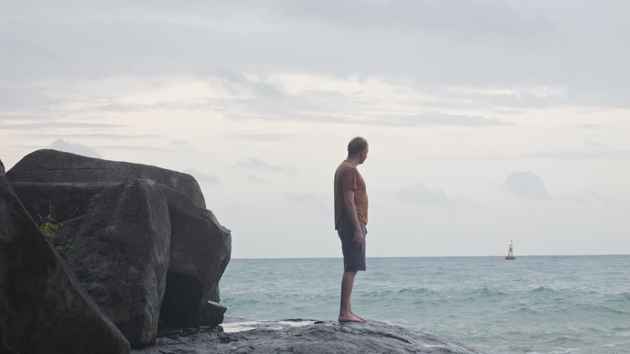 성인 백인 남자가 베트남의  ⁇  트라우 해변의 바위 해안에서 멀리 걸어갑니다.