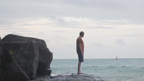 un hombre caucásico adulto se aleja de la costa rocosa en la playa de dam trau en vietnam