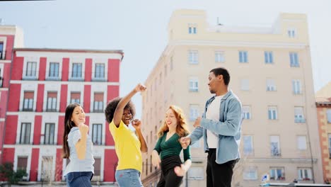 joyful multi-ethnic friends dancing outdoors in the city