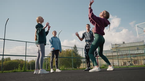 three ladies playing volleyball amongst themselves during outdoor training session, scene shows teamwork, passing the ball back and forth in an open court with background of basketball hoop and fence