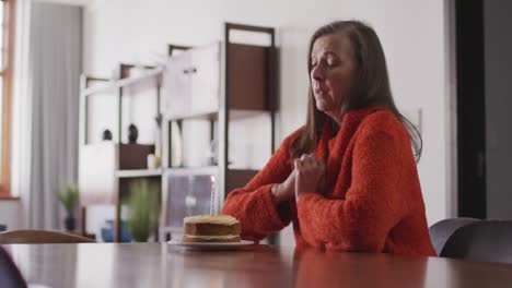 sad woman blowing candle on the cake alone at home