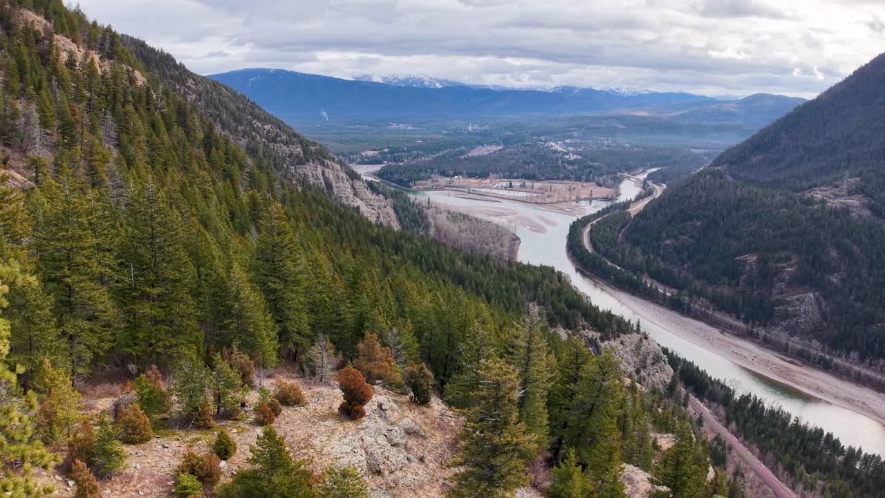 Vista aerea di una valle fluviale da una collina rocciosa coperta da alberi sempreverdi, che cattura il tortuoso fiume Flathead e le montagne distanti vicino a Whitefish, Montana