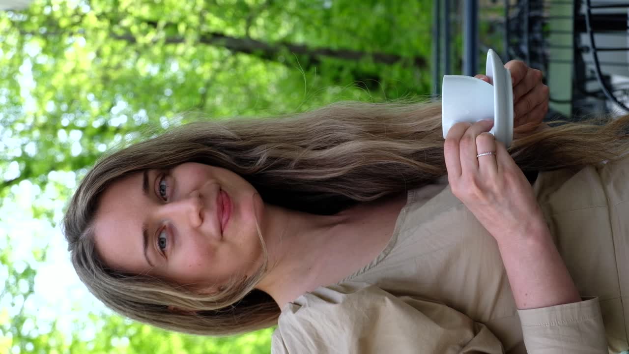 Woman in brown dress drinking coffee outside. Vertical