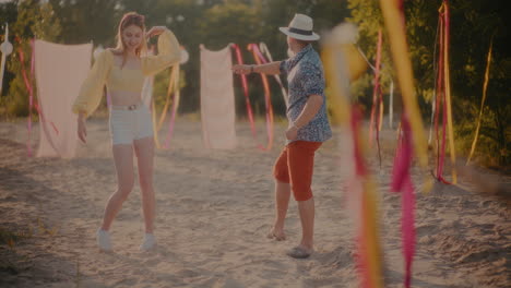 young couple dancing together against sarongs at beach