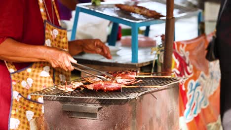 vendor grilling squid at chonburi street market