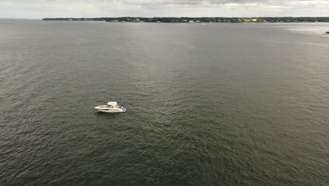 A-low-angle-view-of-a-single-white-boat-anchored-in-the-East-River,-near-the-Throgs-Neck-Bridge-in-NY