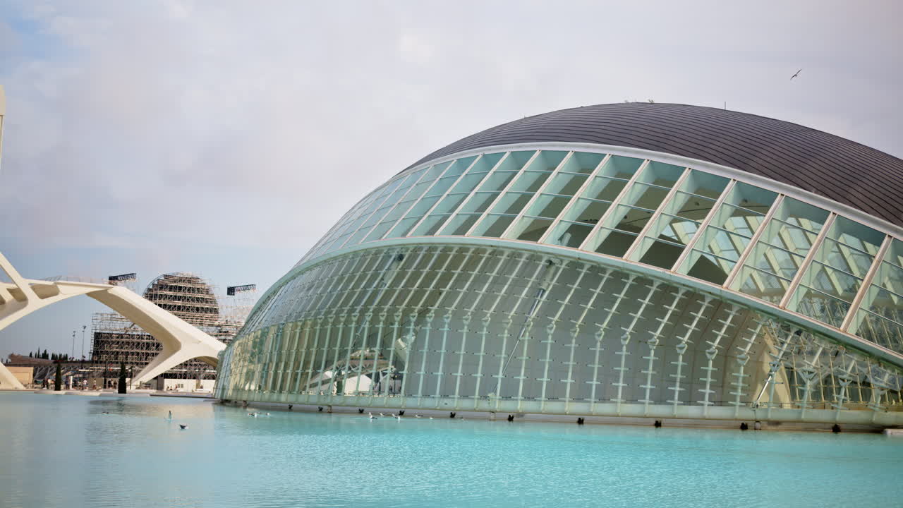 Valencia, Spain - May 28, 2025: White Palau de les Arts letters floating on the pool with the building's sweeping forms behind