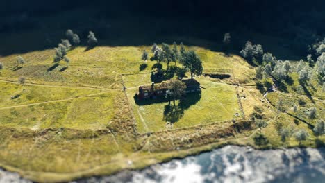 a tilt-shift video of a traditional sod roof house on the river bank