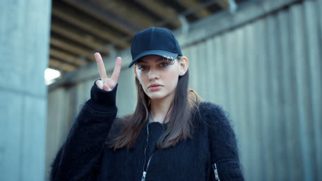 Girl-showing-v-sign-on-city-street.-Fashion-woman-showing-v-gesture-outdoors