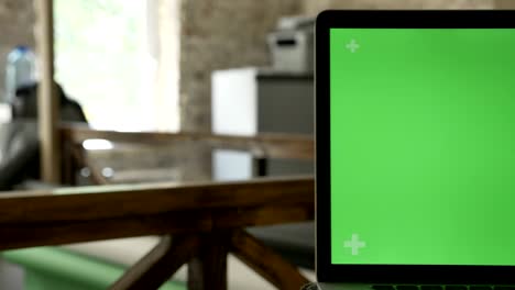 close moving shot of laptop's screen with chromakey in modern office
