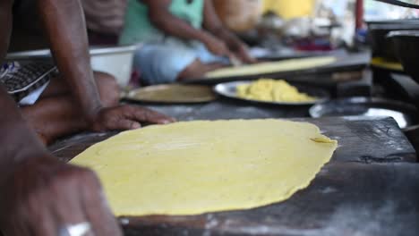 a man sprinkling flour on it and using rolling pin to flatten out the dough