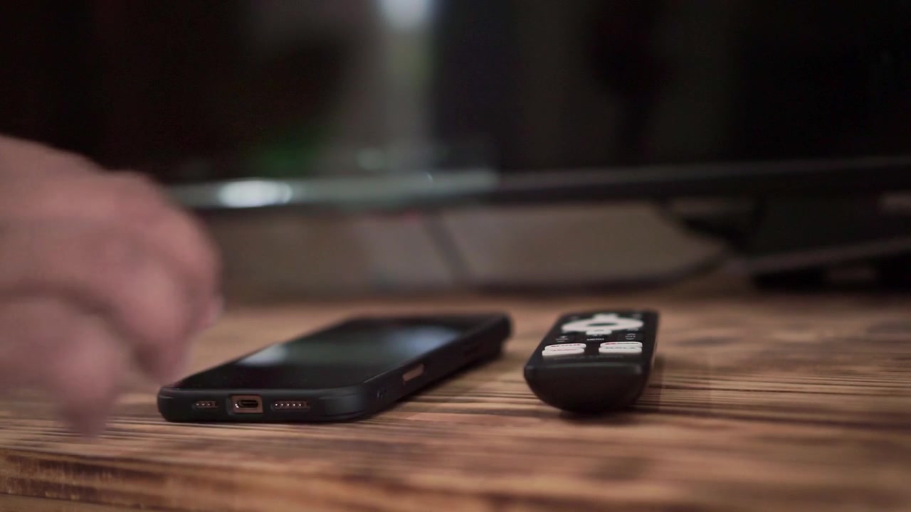 Person setting down watch beside phone and remote control on desk, close up shot, technology and daily routine concept.