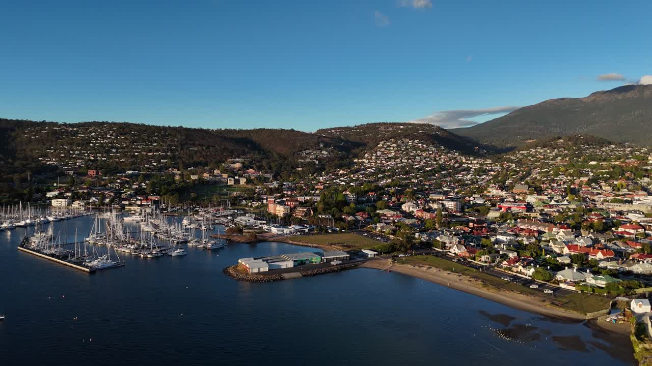 Panoramic shot of the harbor of Hobart city during sunset, aerial shot orbital