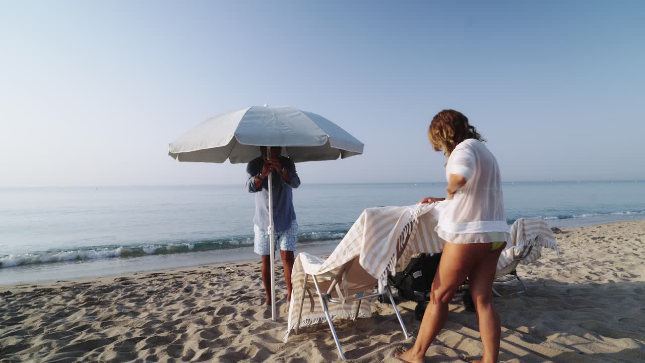 Couple setting up beach chairs and umbrella on the beach