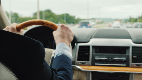 businessman in a business suit driving a car the frame shows the hands of a man on the steering whee