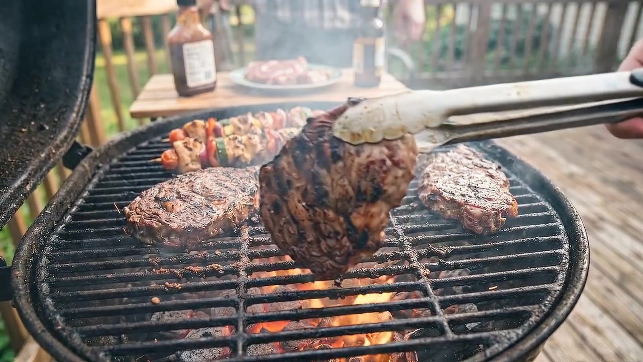 Succulente bistecche di manzo che grigliano su griglia di barbecue fumante in un barbecue in giardino