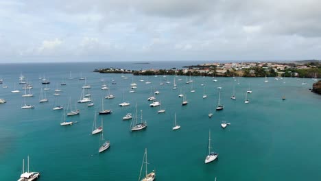 yachts anchored in prickly bay marina, grenada, with coastal buildings, aerial view