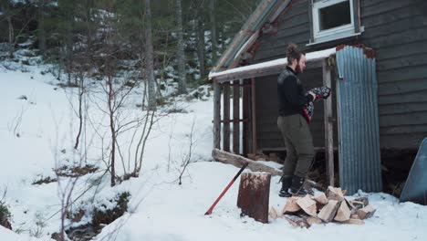 portrait of a caucasian male with axe splitting wood logs during winter