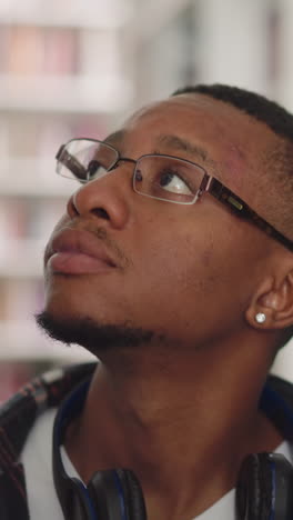 student with eyewear looks around in college library. thoughtful african american man seeks literature in bookstore. education sources for work