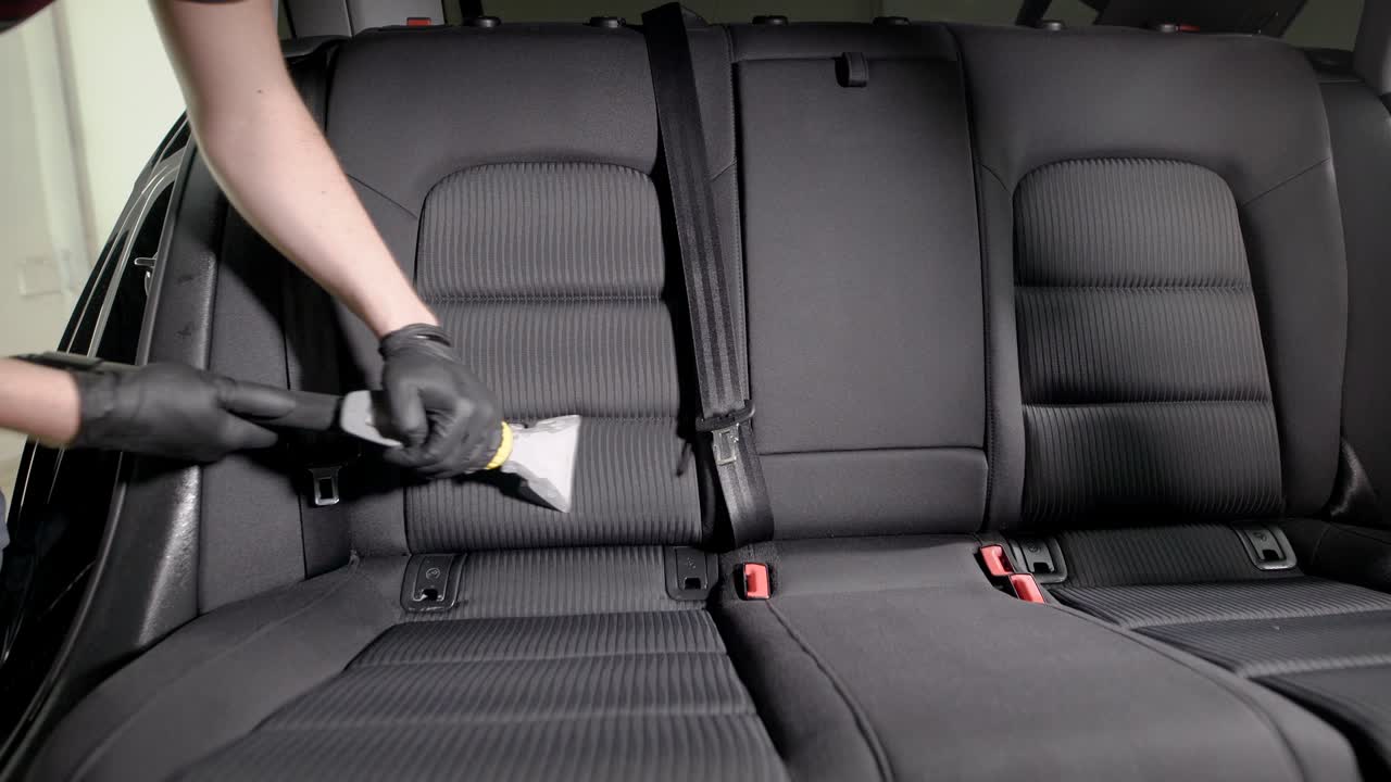 empleado sin rostro aspirando cuidadosamente el asiento del coche