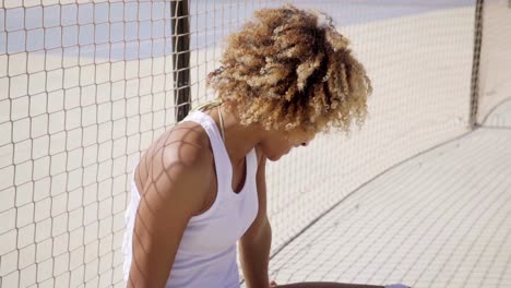 Young-skater-relaxes-beside-tennis-court