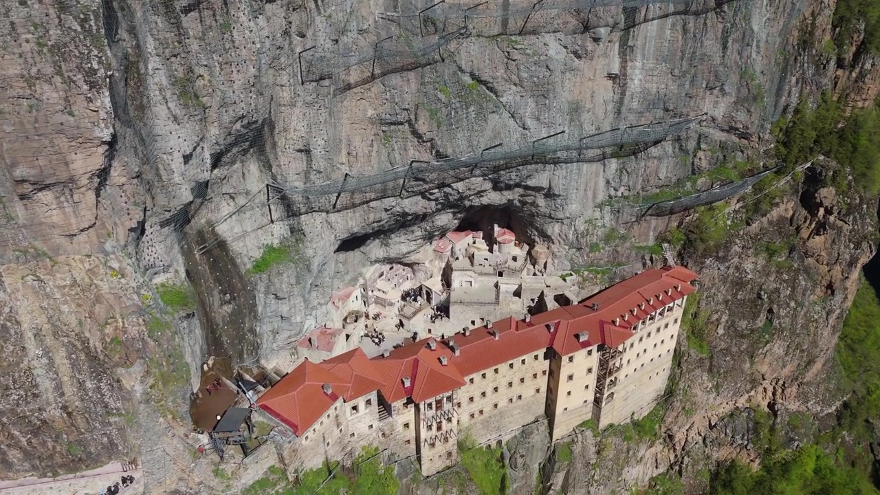top-down drone perspective of the historic Greek Orthodox Sumela Monastery nestled among dense green pine woods in Trabzon, Turkey travel destination