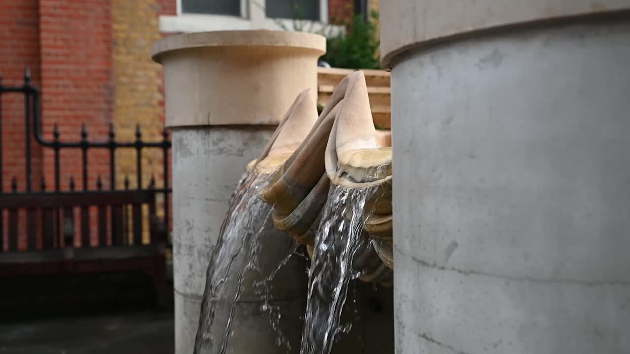 Vista dettagliata della fontana di Covent Garden, che cattura i getti d'acqua, le trame della pietra e l'atmosfera rilassata di questo famoso punto di ritrovo nel centro di Londra