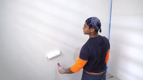 hombre pintor pintando pared blanca usando un rodillo - de cerca