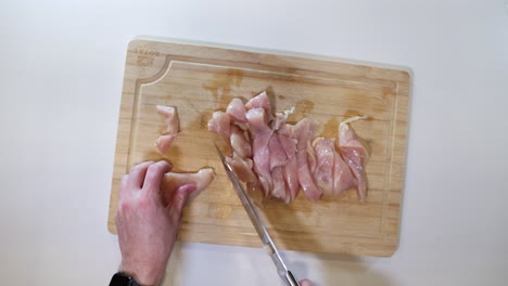 hands cutting raw chicken meat - high angle, close up