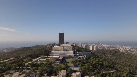 Hohes-Gebäude-Auf-Grünen-Hügeln-Mit-Bäumen-Im-Hintergrund-Stadt-Haifa-Mit-Meer-Und-Hafen,-Israel