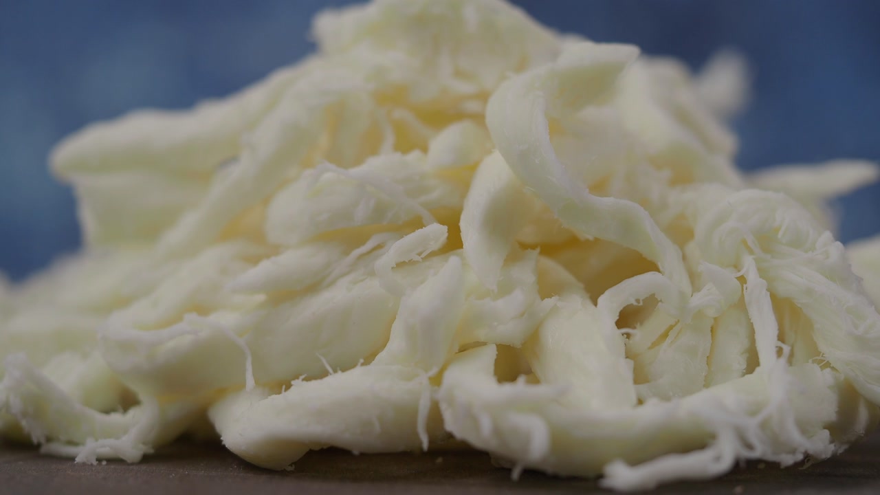 Close-up of Shredded White Cheese on a Blue Background