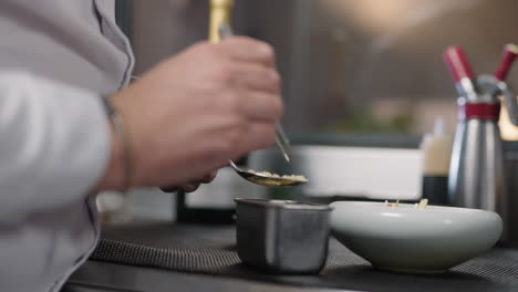 side view of a chef garnishing a dish at a kitchen of a french chef restaurant with burred background