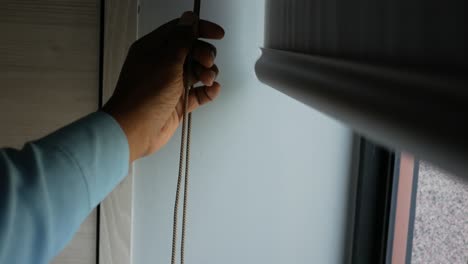 person adjusting window blind cord