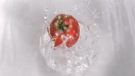 tomato falling into water in super slow motion