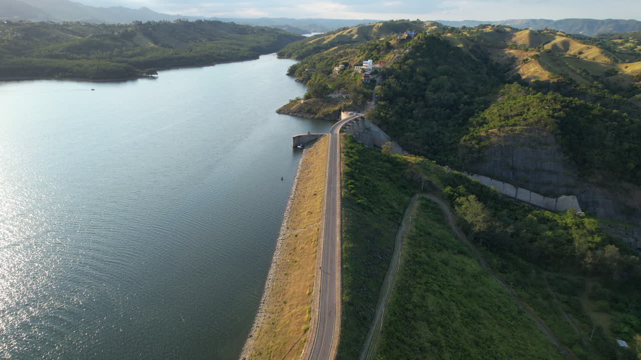 Drone flight over dam with road of lake in Santiago de Los Caballeros at sunset time