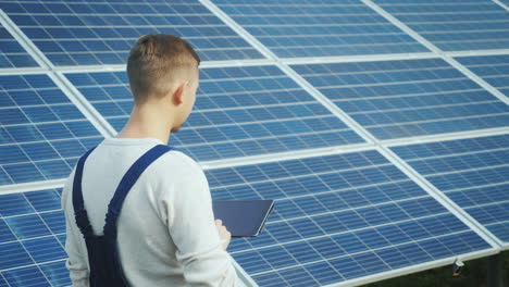 the engineer uses the tablet on the background of solar panels alternative energy and solar energy