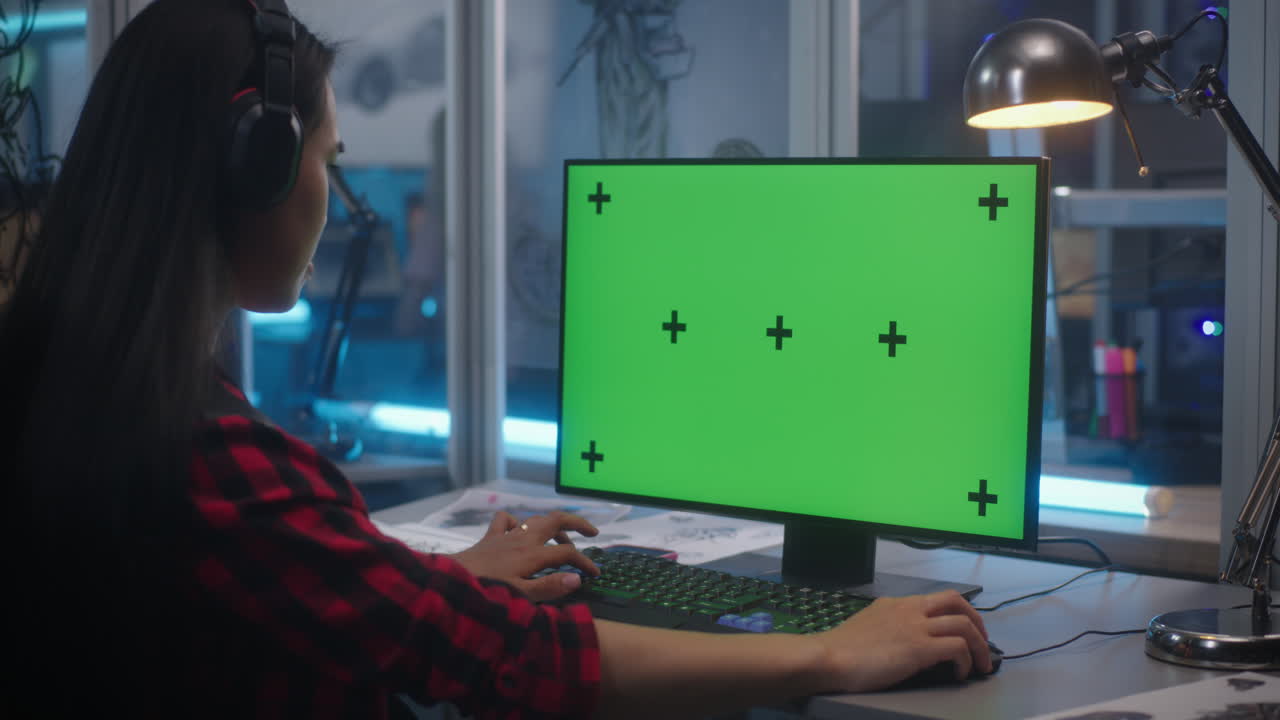 Woman working on a computer with a green screen