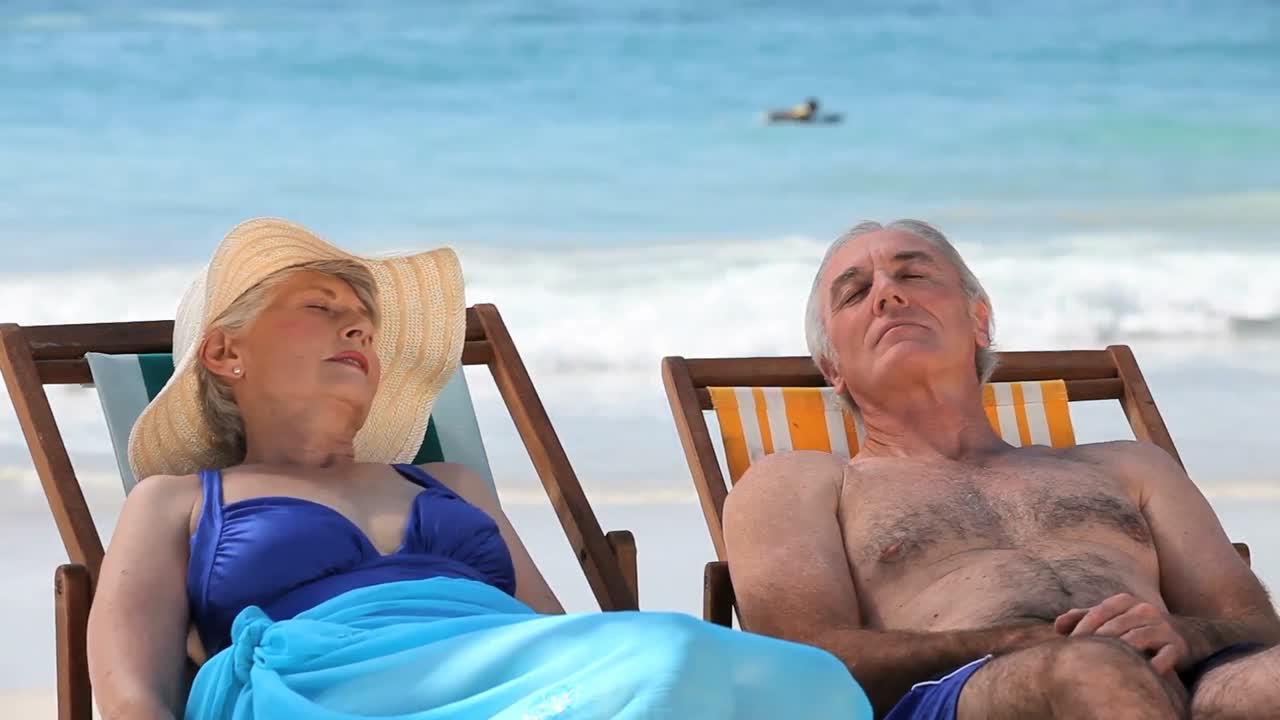 pareja de ancianos relajándose en sillas de playa