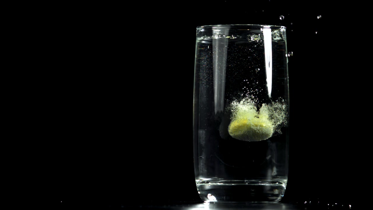 Rallentatore di una compressa effervescente gialla che si dissolve in acqua.