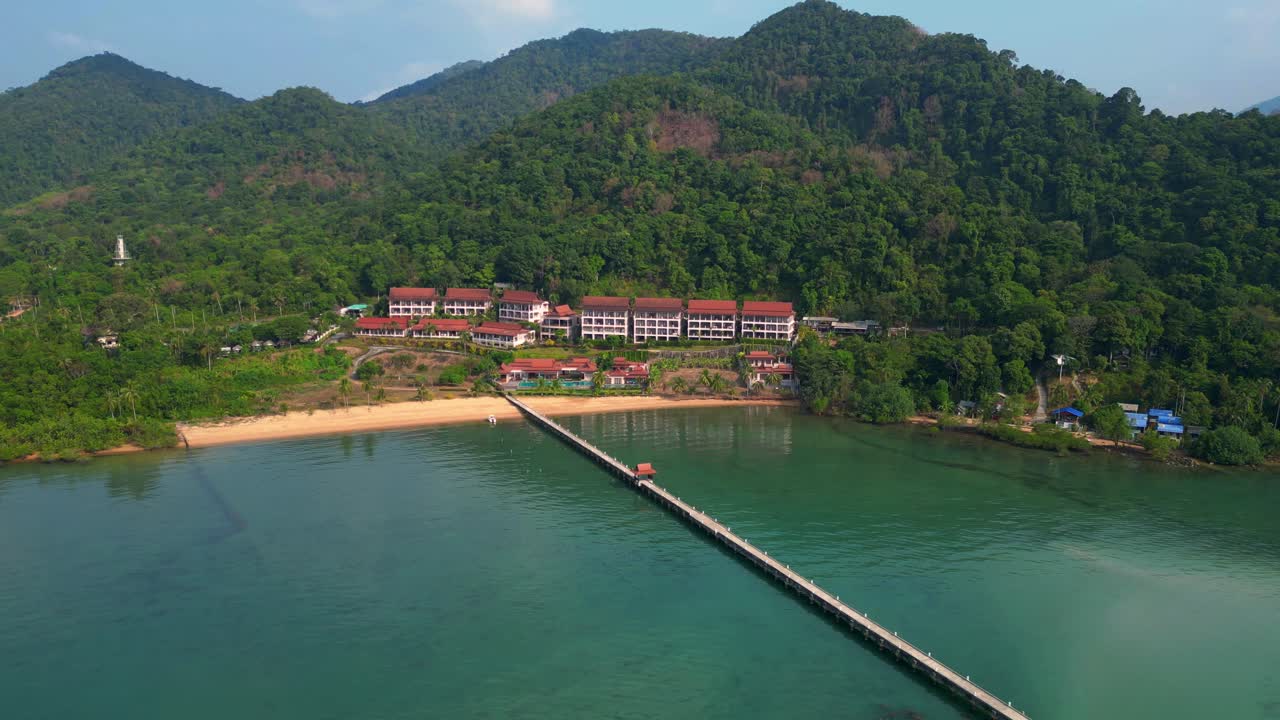 long pier reaching a beautiful resort by the sea in a tropical island koh chang. Magic aerial view flight static tripod hovering drone