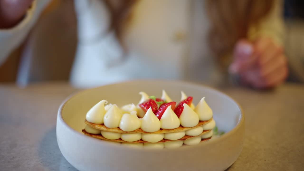 Woman eating Mille feuille cake with strawberry on a plate